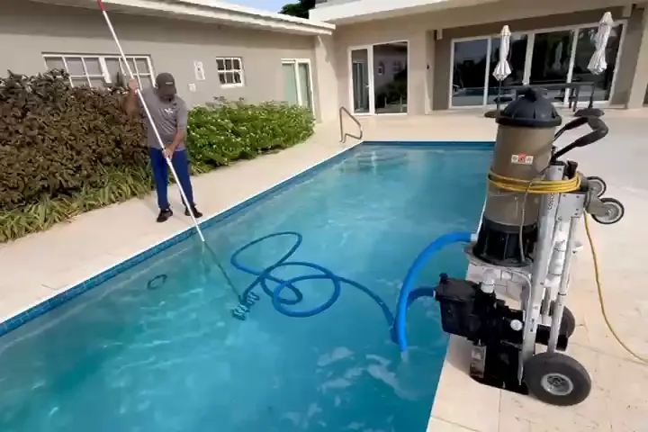 Living Water Aruba technician cleaning a pool with professional vacuum equipment